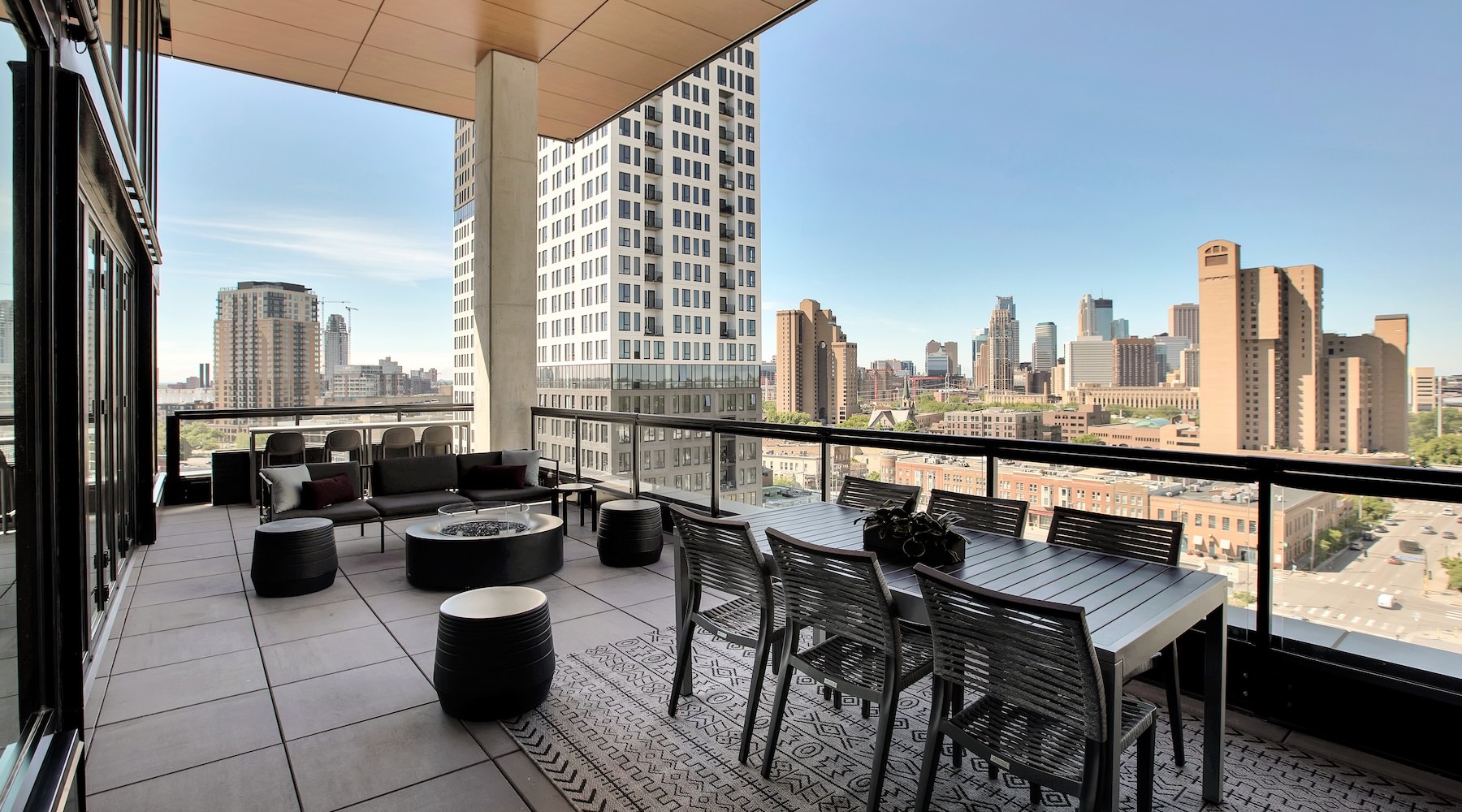 Settle into comfort at Odin a patio with tables and chairs on it with a city skyline in the background